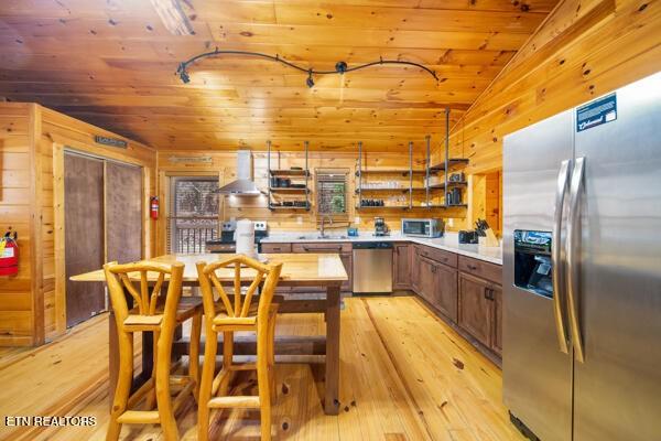 1999 E Mountain View Way, Sevierville, TN 37862 - kitchen with stainless steel appliances, wall chimney range hood, wood ceiling, wooden walls, and light wood-type flooring