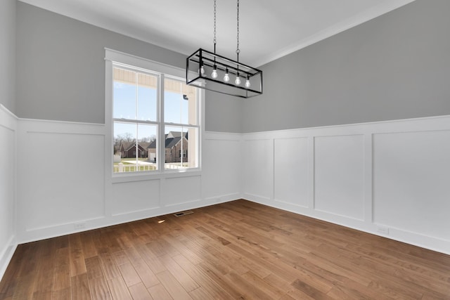 109 Settlers Trce, Tullahoma, TN 37388 - unfurnished dining area with a decorative wall, a wainscoted wall, a chandelier, wood finished floors, and crown molding