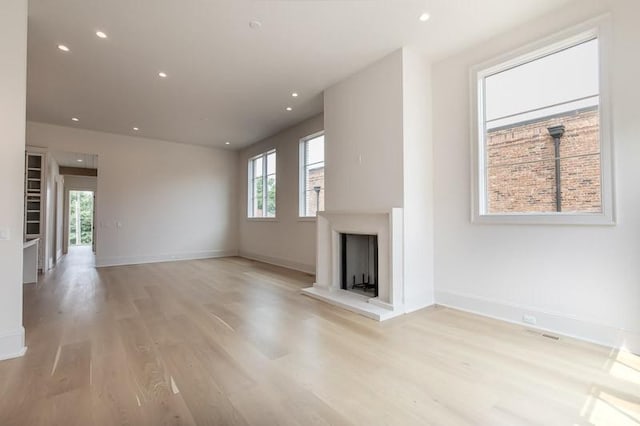 1302B Pillow St, Nashville, TN 37203 - unfurnished living room with light wood-style flooring, a fireplace with raised hearth, recessed lighting, and baseboards