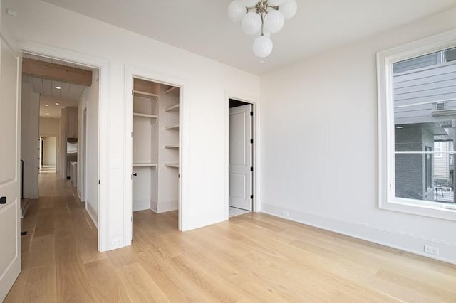 1302B Pillow St, Nashville, TN 37203 - unfurnished bedroom featuring light wood finished floors, a chandelier, a walk in closet, and baseboards