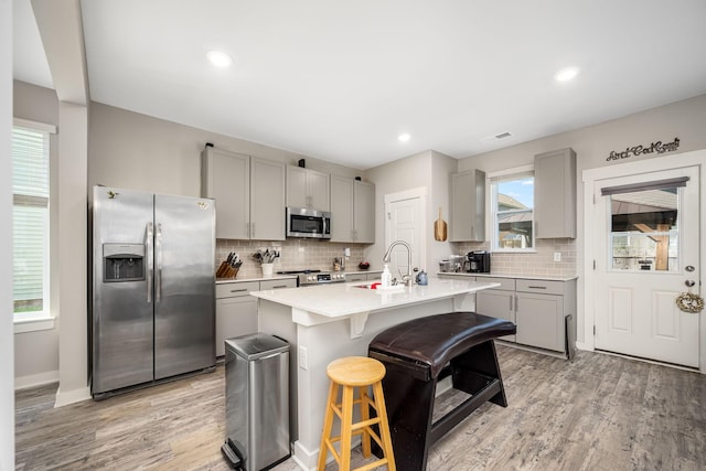 312 Whisper Wood Way, Lebanon, TN 37087 - kitchen featuring appliances with stainless steel finishes, gray cabinets, a kitchen breakfast bar, decorative backsplash, and recessed lighting