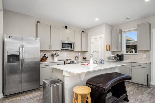 312 Whisper Wood Way, Lebanon, TN 37087 - kitchen featuring appliances with stainless steel finishes, light wood-type flooring, a breakfast bar area, tasteful backsplash, and recessed lighting