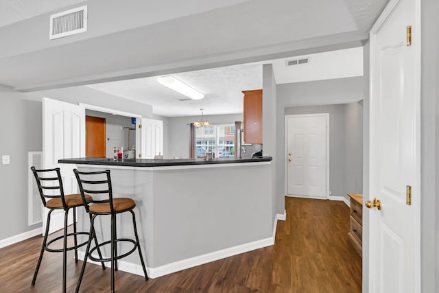 243 Shoshone Pl, Murfreesboro, TN 37128 - kitchen with a breakfast bar area, dark wood-style flooring, dark countertops, and a chandelier