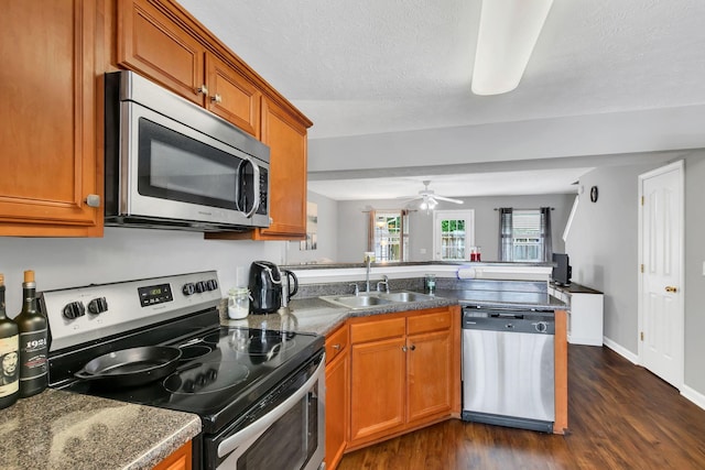 243 Shoshone Pl, Murfreesboro, TN 37128 - kitchen with stainless steel appliances, a peninsula, dark wood-style floors, brown cabinets, and a textured ceiling