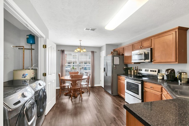 243 Shoshone Pl, Murfreesboro, TN 37128 - kitchen with appliances with stainless steel finishes, washer and dryer, a chandelier, brown cabinets, and dark wood-style flooring