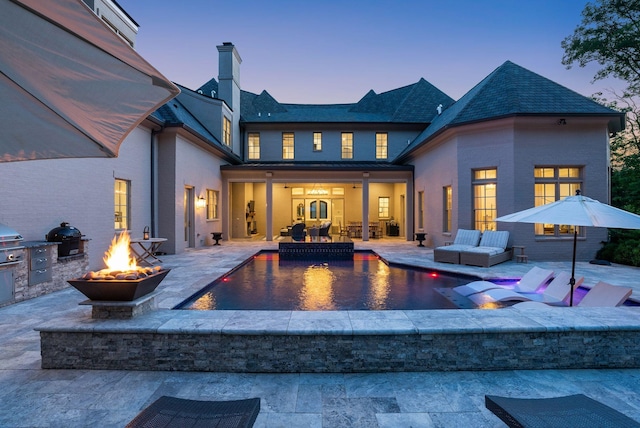 1024 Vaughn Crest Dr, Franklin, TN 37069 - back of property at dusk featuring an outdoor fire pit, an outdoor pool, exterior kitchen, a patio area, and a chimney