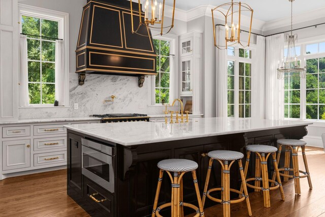 1024 Vaughn Crest Dr, Franklin, TN 37069 - kitchen with stainless steel microwave, a chandelier, light stone countertops, wood finished floors, and ornamental molding