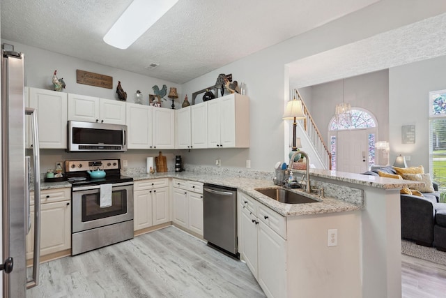 2104 Loudenslager Dr, Thompsons Station, TN 37179 - kitchen featuring appliances with stainless steel finishes, light wood-style flooring, a peninsula, open floor plan, and a textured ceiling