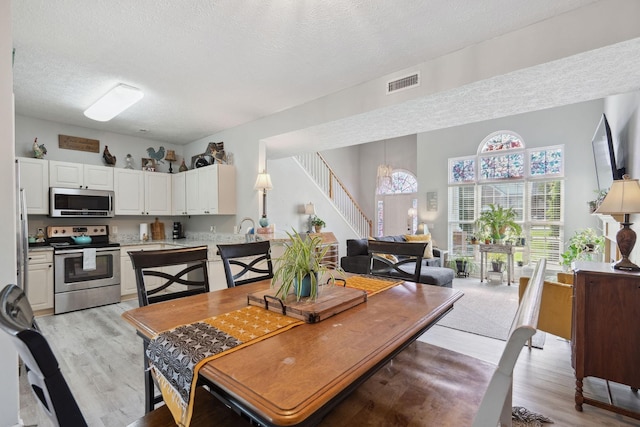2104 Loudenslager Dr, Thompsons Station, TN 37179 - dining area with a textured ceiling, light wood-type flooring, and stairs