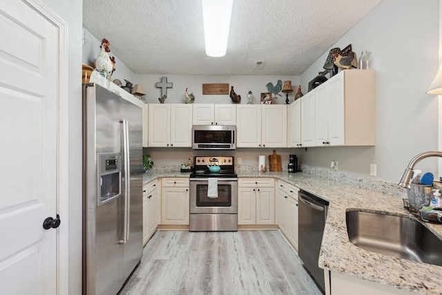 2104 Loudenslager Dr, Thompsons Station, TN 37179 - kitchen featuring appliances with stainless steel finishes, a textured ceiling, light wood-type flooring, and light stone counters