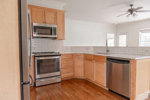 1159 Fairvue Village Ln, Gallatin, TN 37066 - kitchen featuring appliances with stainless steel finishes, light brown cabinetry, a peninsula, tasteful backsplash, and ornamental molding