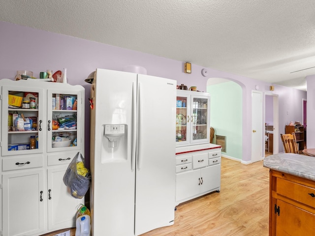 1574 Midway Rd, Sewanee, TN 37375 - kitchen featuring white refrigerator with ice dispenser, light wood-type flooring, a textured ceiling, arched walkways, and light countertops
