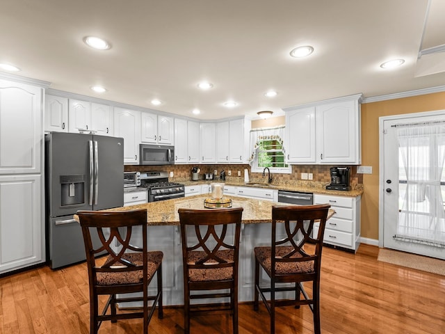 1574 Midway Rd, Sewanee, TN 37375 - kitchen featuring appliances with stainless steel finishes, white cabinets, a breakfast bar, tasteful backsplash, and ornamental molding