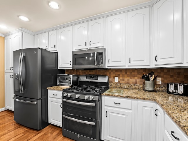 1574 Midway Rd, Sewanee, TN 37375 - kitchen featuring appliances with stainless steel finishes, white cabinets, light wood-style floors, decorative backsplash, and stone counters
