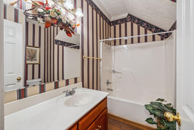 6873 Giles Hill Rd, College Grove, TN 37046 - full bath with wallpapered walls, vanity, wood finished floors, bathtub / shower combination, and a textured ceiling