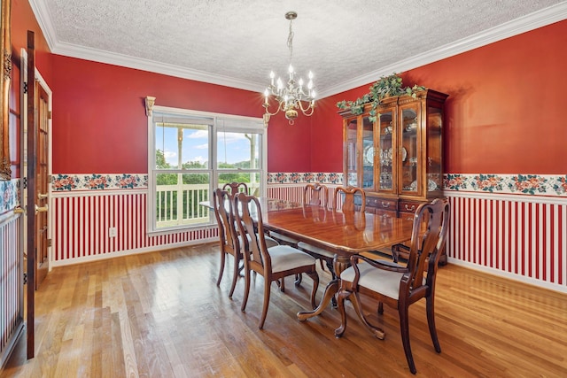 6873 Giles Hill Rd, College Grove, TN 37046 - dining space with a chandelier, a textured ceiling, wood finished floors, crown molding, and wainscoting