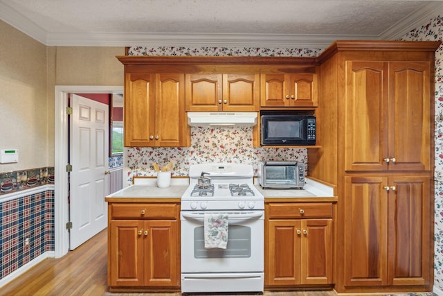 6873 Giles Hill Rd, College Grove, TN 37046 - kitchen with gas range gas stove, black microwave, under cabinet range hood, wallpapered walls, and light countertops