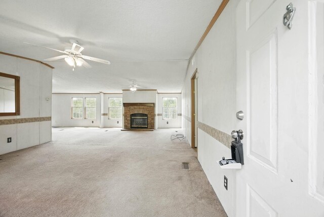 947 Buck Branch Rd, Charlotte, TN 37036 - unfurnished living room with a ceiling fan, light carpet, a glass covered fireplace, ornamental molding, and a textured ceiling