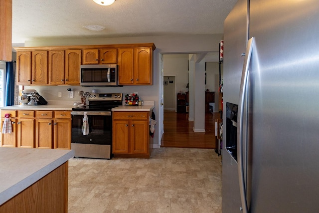 674 Superior Ln, Clarksville, TN 37043 - kitchen featuring appliances with stainless steel finishes, light countertops, brown cabinets, and a textured ceiling