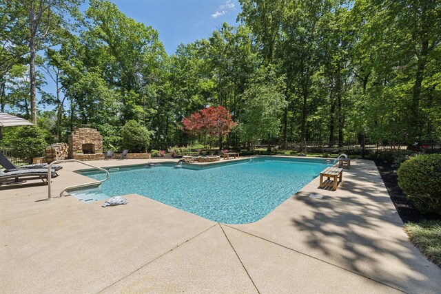 1150 Deer Run Rd, Murfreesboro, TN 37128 - view of swimming pool featuring a patio, an outdoor stone fireplace, and view of scattered trees