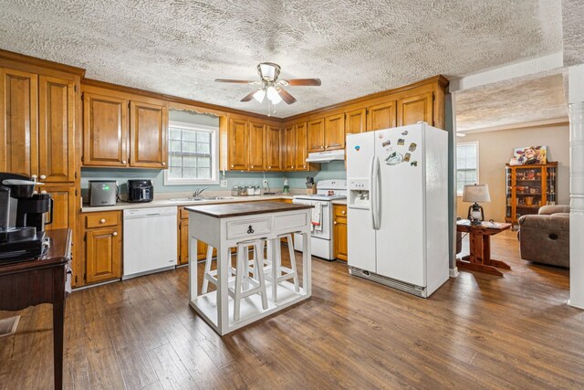 8663 Dog Creek Rd, Primm Springs, TN 38476 - kitchen featuring white appliances, under cabinet range hood, brown cabinetry, dark wood-style floors, and a ceiling fan