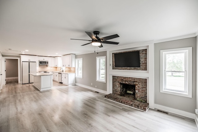 1108 Pruitt Ln, Gallatin, TN 37066 - unfurnished living room featuring ornamental molding, ceiling fan, a fireplace, recessed lighting, and light wood finished floors