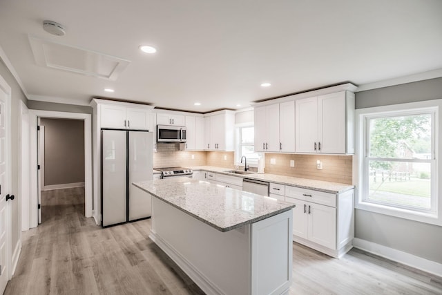 1108 Pruitt Ln, Gallatin, TN 37066 - kitchen with appliances with stainless steel finishes, white cabinets, decorative backsplash, a center island, and light wood finished floors