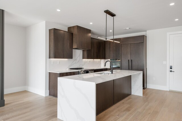 321 31st Ave N Unit B1A A, Nashville, TN 37203 - kitchen with modern cabinets, dark brown cabinetry, light wood finished floors, a center island with sink, and recessed lighting