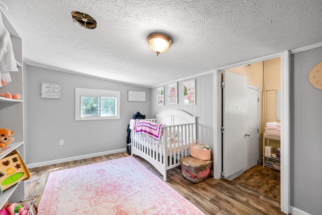 154 Crains Landing Rd, Dover, TN 37058 - bedroom featuring wood finished floors, a textured ceiling, a crib, lofted ceiling, and baseboards