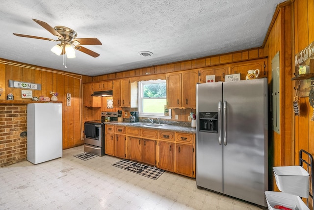 154 Crains Landing Rd, Dover, TN 37058 - kitchen with appliances with stainless steel finishes, brown cabinetry, under cabinet range hood, wood walls, and light flooring
