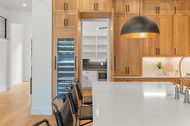 2915 Compton Rd, Nashville, TN 37215 - kitchen with decorative backsplash, stainless steel microwave, light stone counters, light wood finished floors, and baseboards