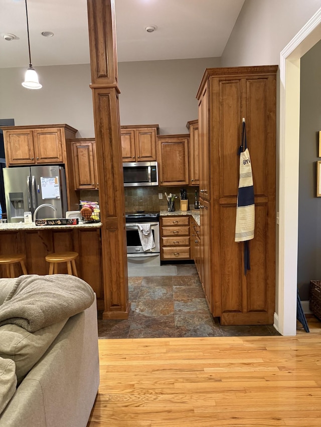 31 Chickory Ln, Monteagle, TN 37356 - kitchen featuring appliances with stainless steel finishes, brown cabinetry, decorative backsplash, hanging light fixtures, and a breakfast bar