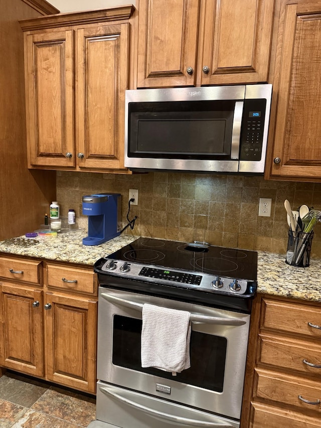 31 Chickory Ln, Monteagle, TN 37356 - kitchen featuring appliances with stainless steel finishes, brown cabinets, backsplash, and light stone counters
