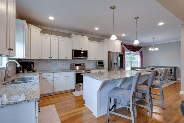 2001 Katach Ct, Spring Hill, TN 37174 - kitchen with appliances with stainless steel finishes, ornamental molding, backsplash, white cabinetry, and a kitchen island