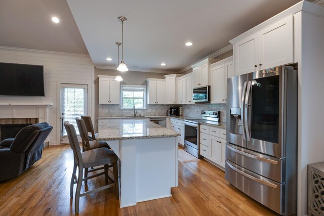 2001 Katach Ct, Spring Hill, TN 37174 - kitchen featuring stainless steel appliances, open floor plan, ornamental molding, light wood-style floors, and white cabinets