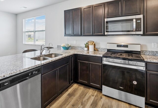 1013 Pepper Stone Dr, Lebanon, TN 37087 - kitchen featuring appliances with stainless steel finishes, light wood-type flooring, light stone counters, and dark brown cabinetry