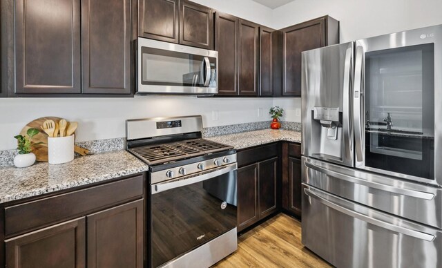 1013 Pepper Stone Dr, Lebanon, TN 37087 - kitchen featuring stainless steel appliances, dark brown cabinets, light stone counters, and light wood-style floors