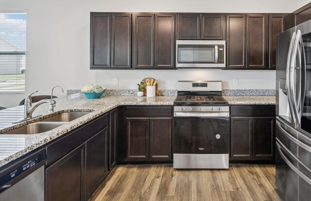 1013 Pepper Stone Dr, Lebanon, TN 37087 - kitchen with stainless steel appliances, light wood-style floors, dark brown cabinetry, and light stone countertops
