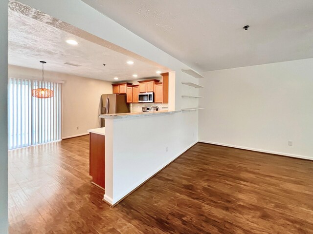 4017 Pavati Trce, Spring Hill, TN 37174 - kitchen with appliances with stainless steel finishes, baseboards, a peninsula, wood finished floors, and light countertops
