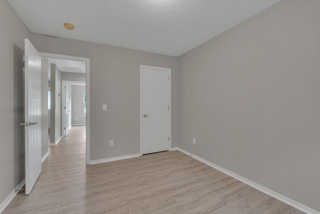 7352 Hidden Lake Cir, Fairview, TN 37062 - unfurnished bedroom featuring attic access, light wood finished floors, and a textured ceiling