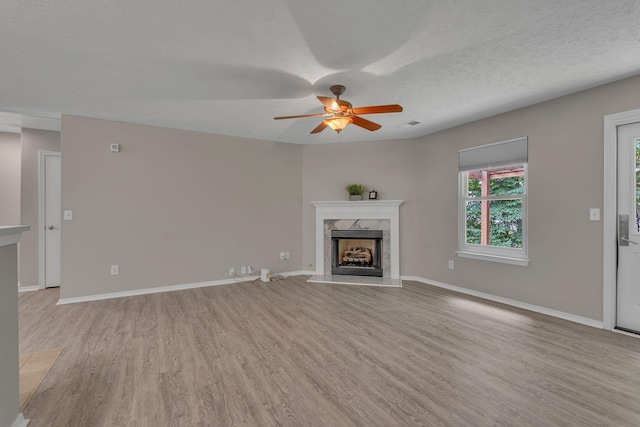 7352 Hidden Lake Cir, Fairview, TN 37062 - unfurnished living room featuring light wood-style flooring, a high end fireplace, a ceiling fan, and a textured ceiling