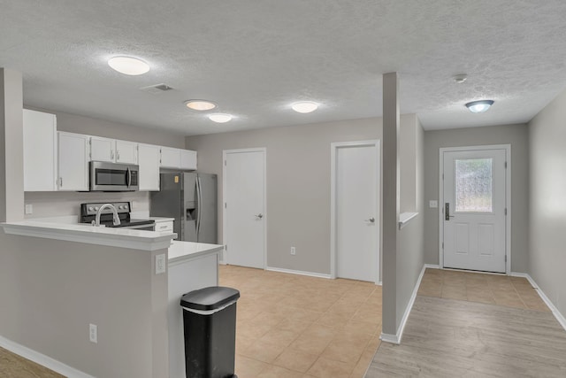 7352 Hidden Lake Cir, Fairview, TN 37062 - kitchen with appliances with stainless steel finishes, light countertops, white cabinetry, a peninsula, and a textured ceiling