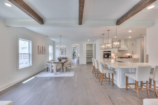 4025 Singing Creek Dr, Franklin, TN 37064 - kitchen featuring a chandelier, a kitchen bar, light wood-style floors, light countertops, and white cabinets