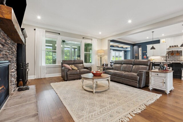 6013 Blackwell Ln, Franklin, TN 37064 - living area featuring a stone fireplace, dark wood-style flooring, a ceiling fan, crown molding, and recessed lighting