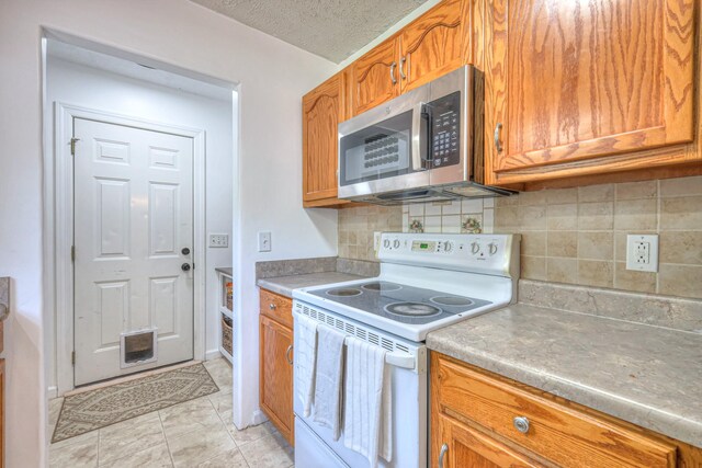 168 N Wagon Trl, Murfreesboro, TN 37128 - kitchen featuring stainless steel microwave, electric stove, brown cabinetry, tasteful backsplash, and light countertops