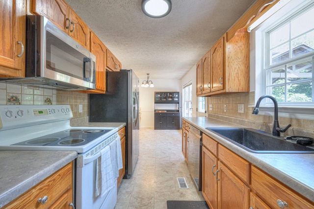 168 N Wagon Trl, Murfreesboro, TN 37128 - kitchen featuring appliances with stainless steel finishes, brown cabinetry, a textured ceiling, tasteful backsplash, and a chandelier