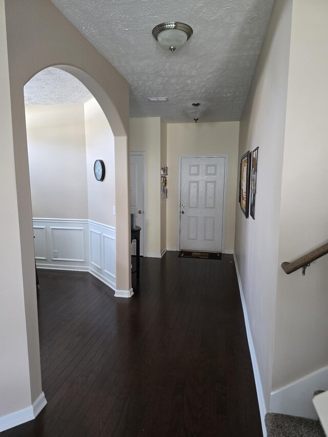 1736 Bellamy Ln, Murfreesboro, TN 37128 - hallway featuring arched walkways, a textured ceiling, dark wood-type flooring, and a wainscoted wall