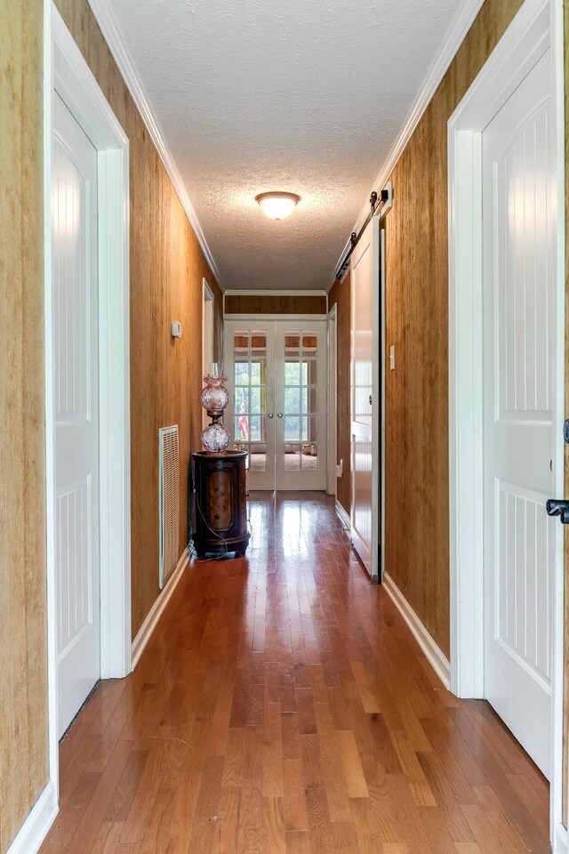 554 Hickman Shores Rd, Dover, TN 37058 - corridor featuring crown molding, hardwood / wood-style floors, french doors, a barn door, and a textured ceiling
