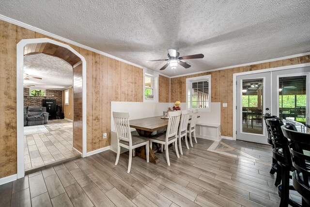 554 Hickman Shores Rd, Dover, TN 37058 - dining room with ceiling fan, wooden walls, crown molding, wood finished floors, and arched walkways