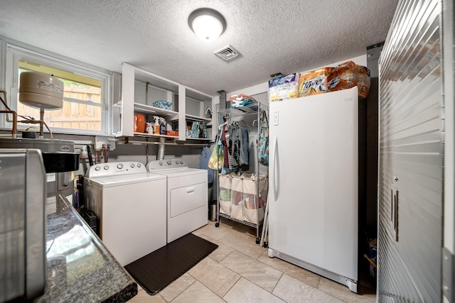 554 Hickman Shores Rd, Dover, TN 37058 - laundry area featuring washing machine and dryer, a textured ceiling, water heater, and light tile patterned flooring